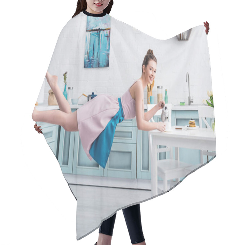 Personality  Happy Beautiful Young Woman Levitating In Air And Pouring Tea In Cup From Teapot In Kitchen Hair Cutting Cape