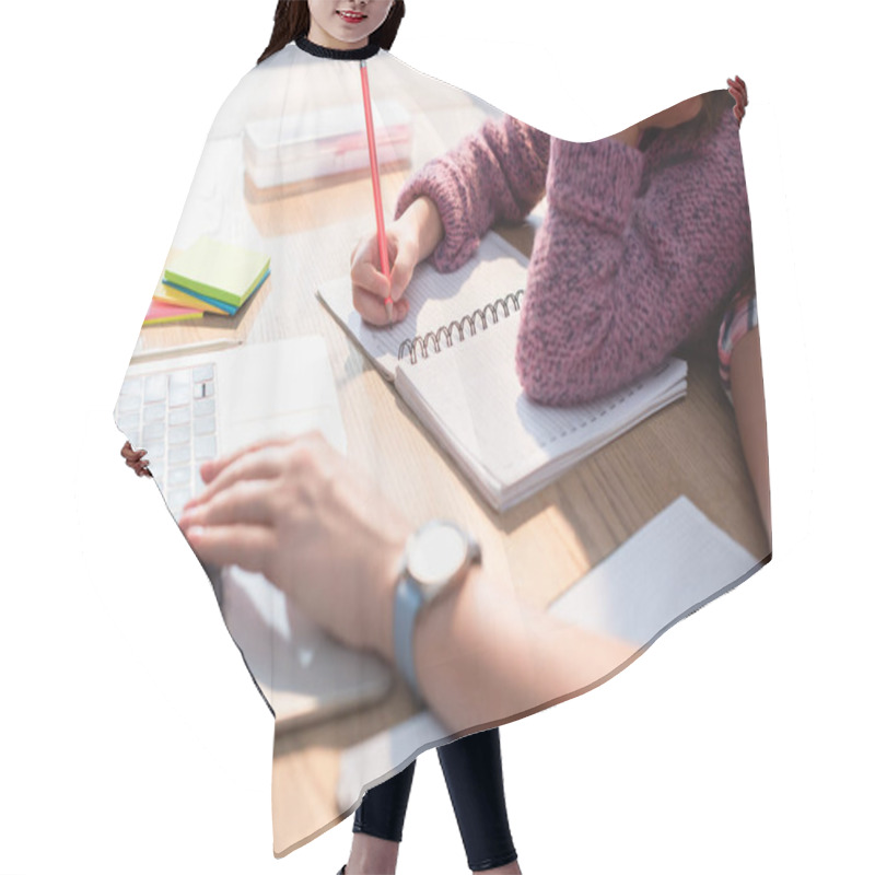 Personality  Cropped View Of Daughter Writing In Notebook At Desk With Blurred Mother Typing On Laptop On Foreground Hair Cutting Cape