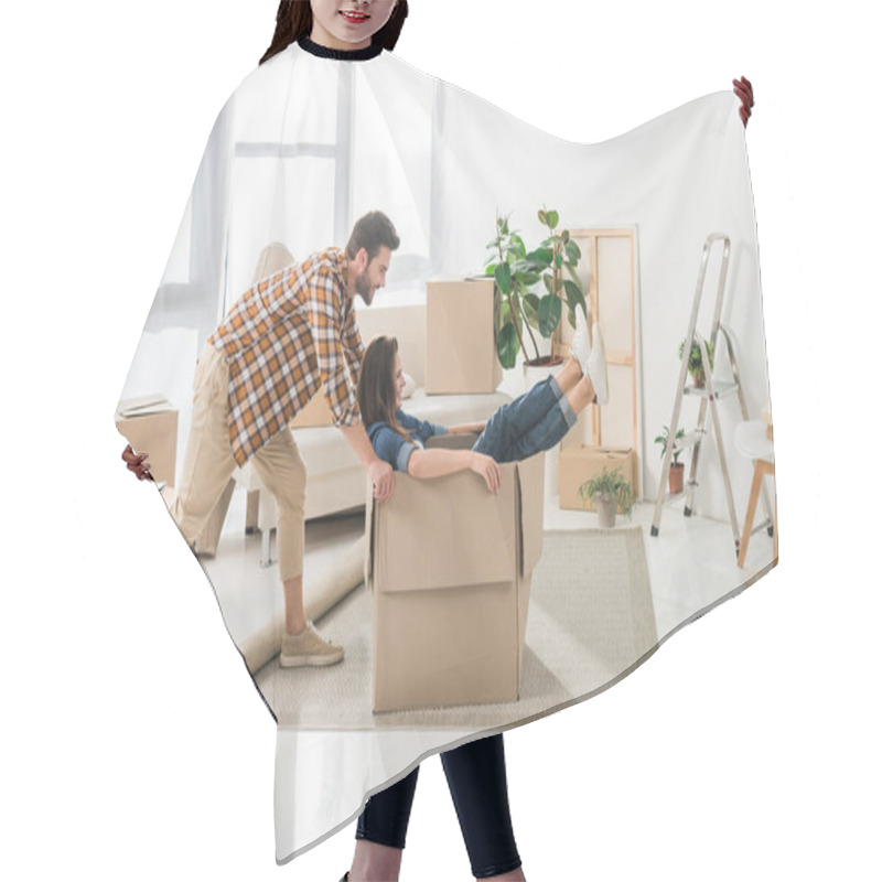 Personality  Side View Of Couple Having Fun With Cardboard Box At New House, Moving Home Concept Hair Cutting Cape