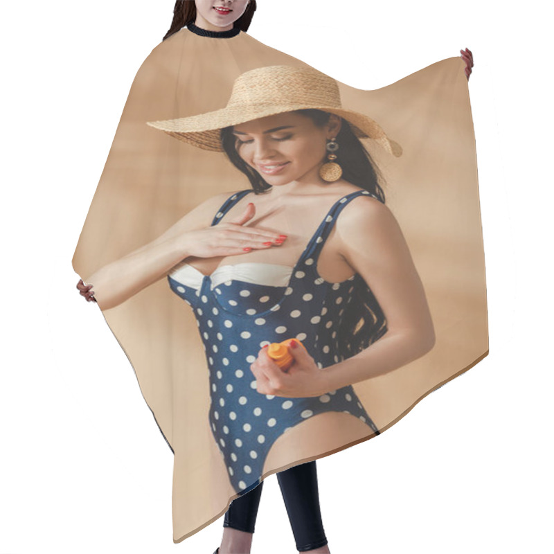 Personality  Smiling Sexy Brunette Woman In Polka Dot Swimsuit And Straw Hat Applying Sunscreen On Breast On Beige Background Hair Cutting Cape