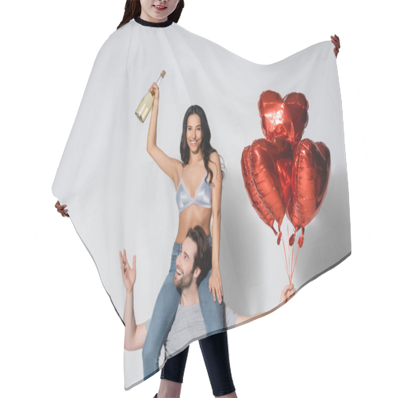 Personality  Smiling Man With Heart-shaped Balloons Piggybacking Woman Holding Champagne On Grey Hair Cutting Cape