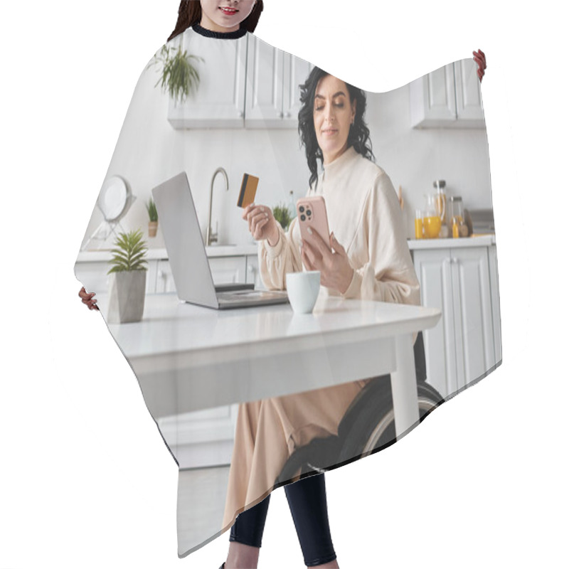 Personality  Woman In A Wheelchair Managing Finances And Working Online Using A Laptop In Her Kitchen. Hair Cutting Cape