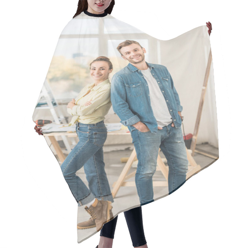 Personality  Happy Young Couple Standing Back To Back And Smiling At Camera During House Repair Hair Cutting Cape