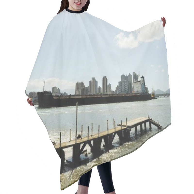 Personality  A Large Cargo Ship Sails Near An Urban Skyline With Tall Buildings, Under A Partly Cloudy Sky, With A Wooden Pier In The Foreground And Calm Waters Reflecting The Scene. Hair Cutting Cape