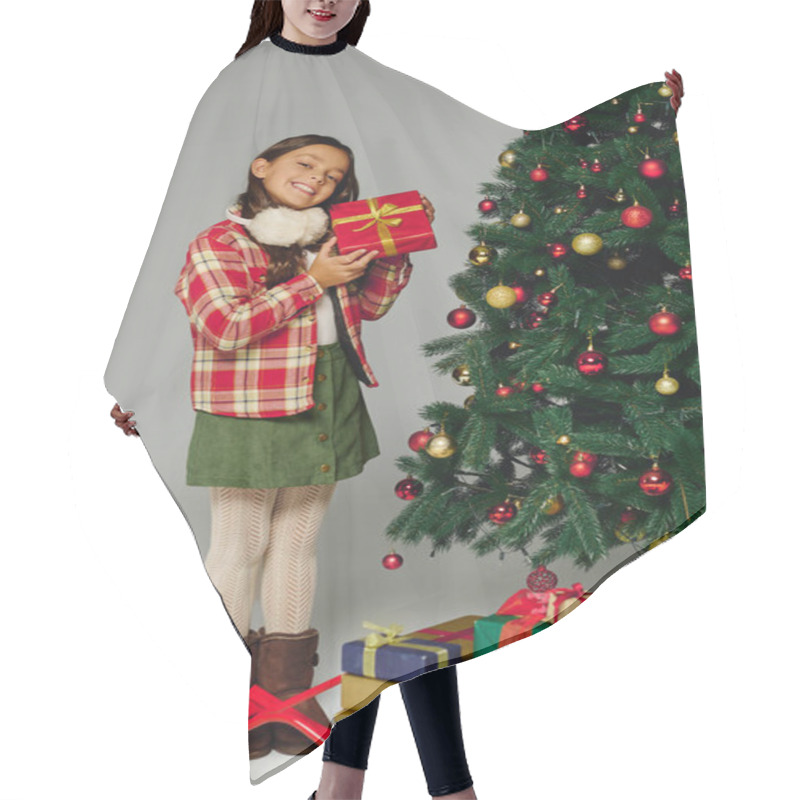 Personality  Little Girl In Festive Attire Smiles While Holding A Gift Near A Decorated Christmas Tree. Hair Cutting Cape