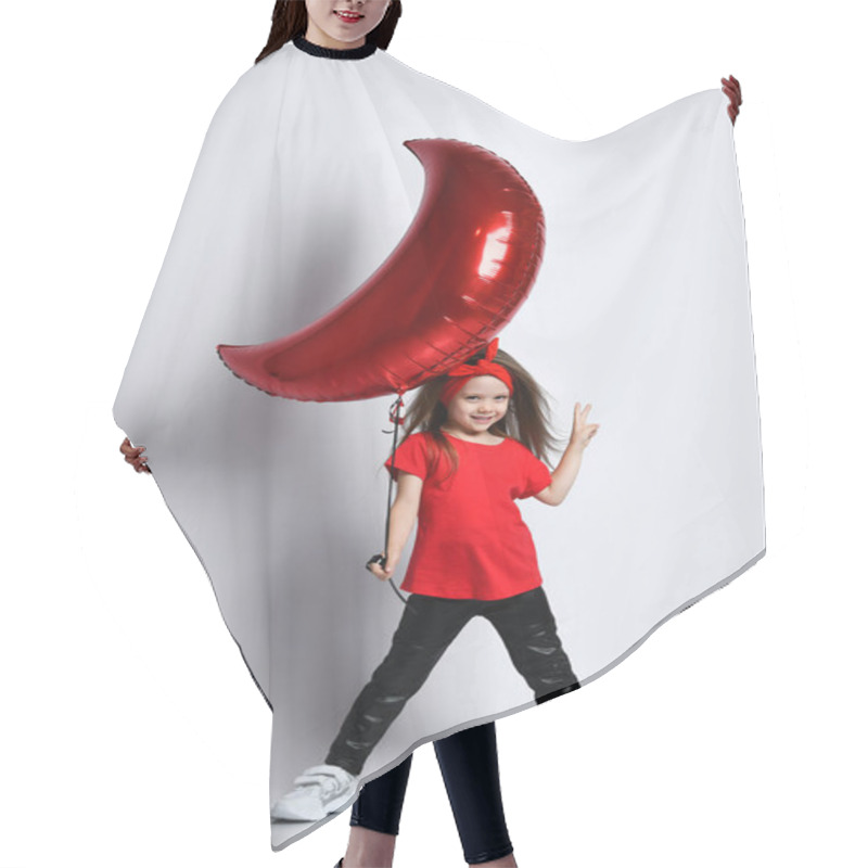 Personality  Small Girl In T-shirt, Trousers, Sneakers And Hair Accessory Standing, Holding Moon Shaped Balloon In Hand And Showing Peace Sign Hair Cutting Cape