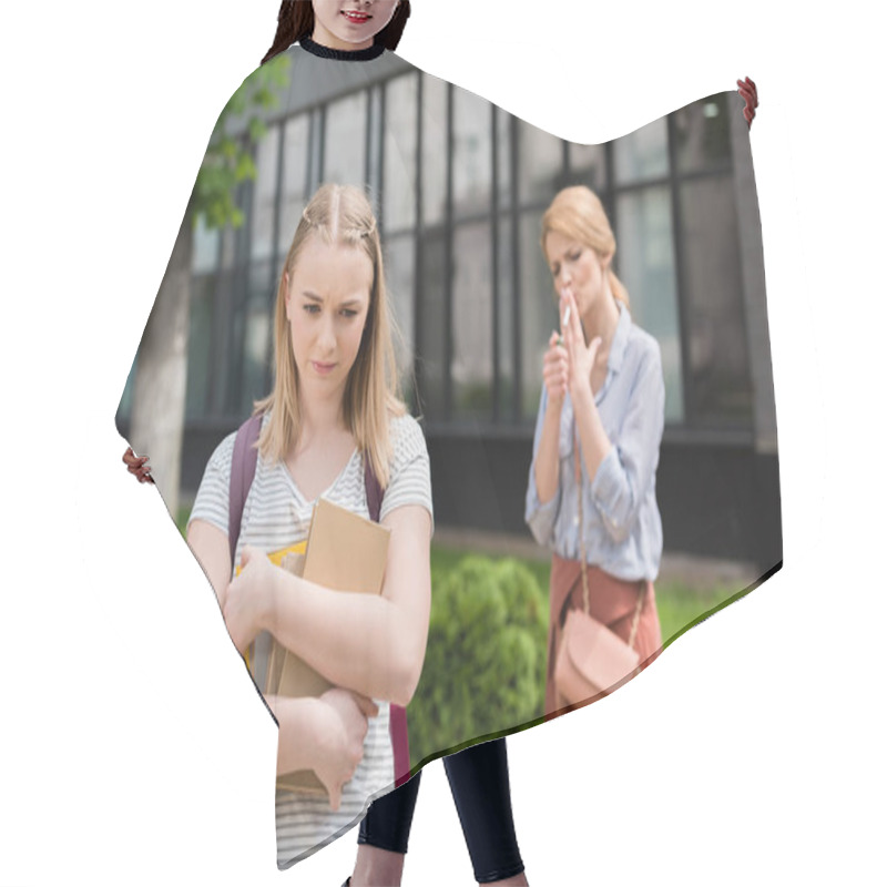 Personality  Disappointed Teen Daughter With Books Looking Down While Her Mother Smoking Cigarette Blurred On Background Hair Cutting Cape