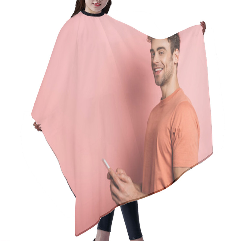 Personality  Cheerful Young Man Smiling At Camera While Chatting On Smartphone On Pink Background Hair Cutting Cape