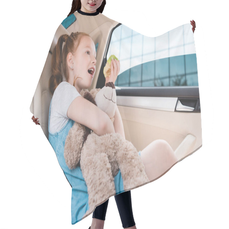 Personality  Side View Of Emotional Kid With Teddy Bear And Fresh Apple In Car Hair Cutting Cape