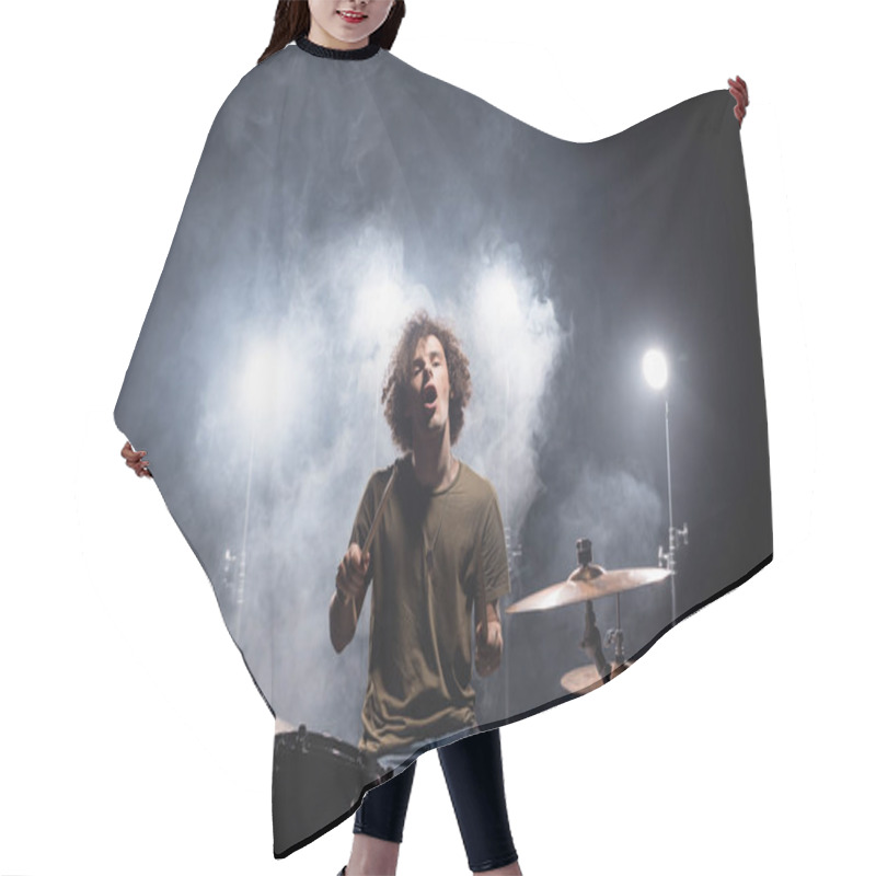 Personality  Excited Curly Drummer With Open Mouth Sitting At Drum Kit With Smoke And Backlit On Black  Hair Cutting Cape