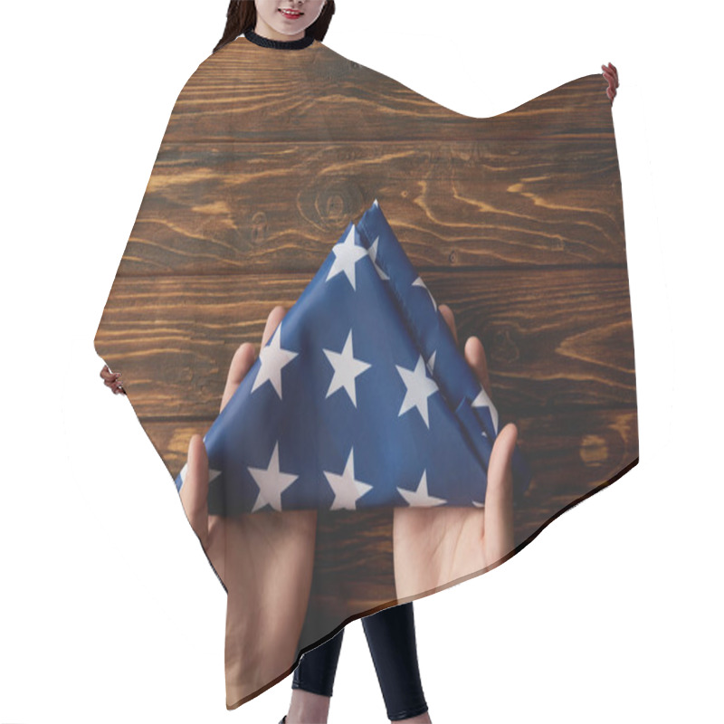 Personality  Cropped Shot Of Man Holding Folded United States Flag On Wooden Background Hair Cutting Cape