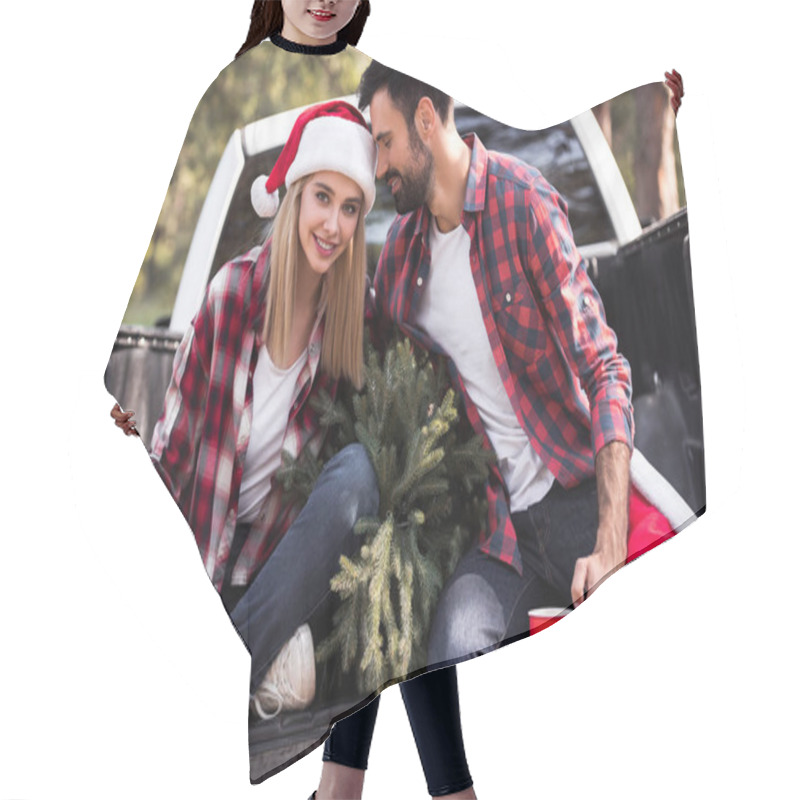 Personality  Beautiful Couple In Santa Hats Holding Red Cups While Sitting On Pickup Truck With Fir Tree For Christmas  Hair Cutting Cape