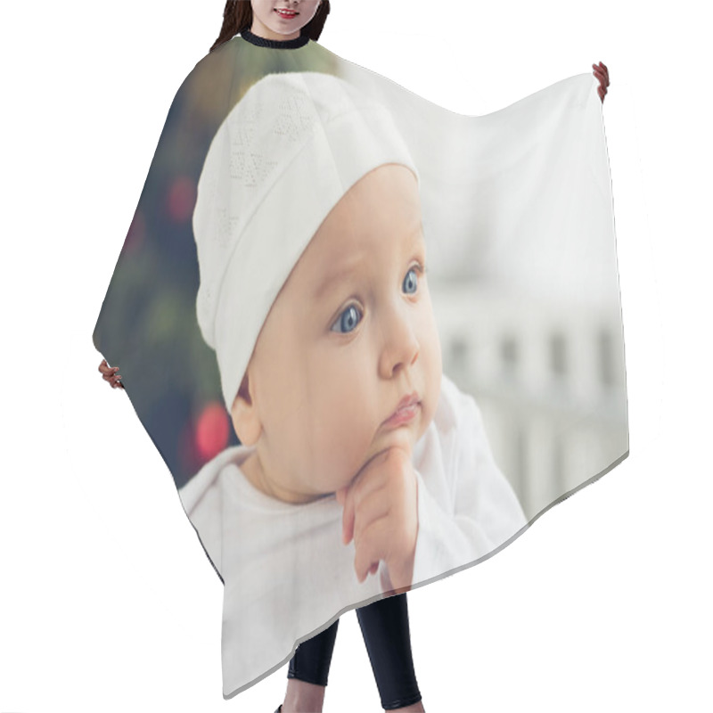 Personality  Close-up Portrait Of Cute Little Baby In White Hat With Blurred Christmas Tree On Background Hair Cutting Cape