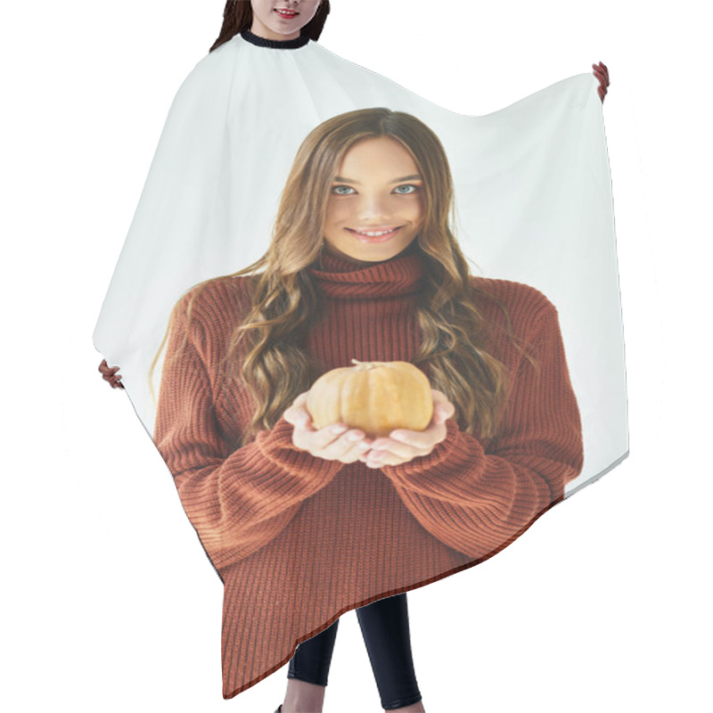 Personality  A Young Woman In A Cozy Sweater Smiles, Presenting A Small Pumpkin For Halloween. Hair Cutting Cape