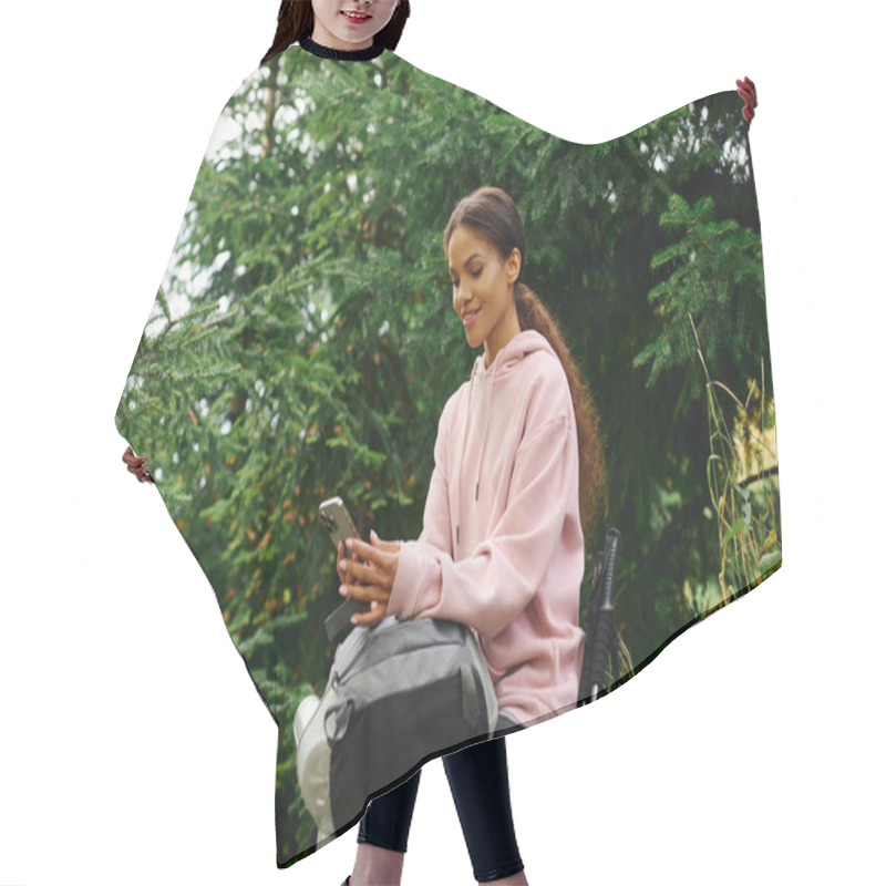 Personality  A Young African American Woman Sits On A Rock, Checking Her Phone While Surrounded By Autumn Foliage. Hair Cutting Cape