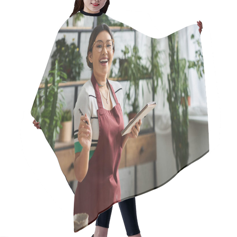 Personality  A Young Woman In An Apron Smiles As She Takes Inventory In Her Plant Store, Surrounded By Lush Greenery. Hair Cutting Cape