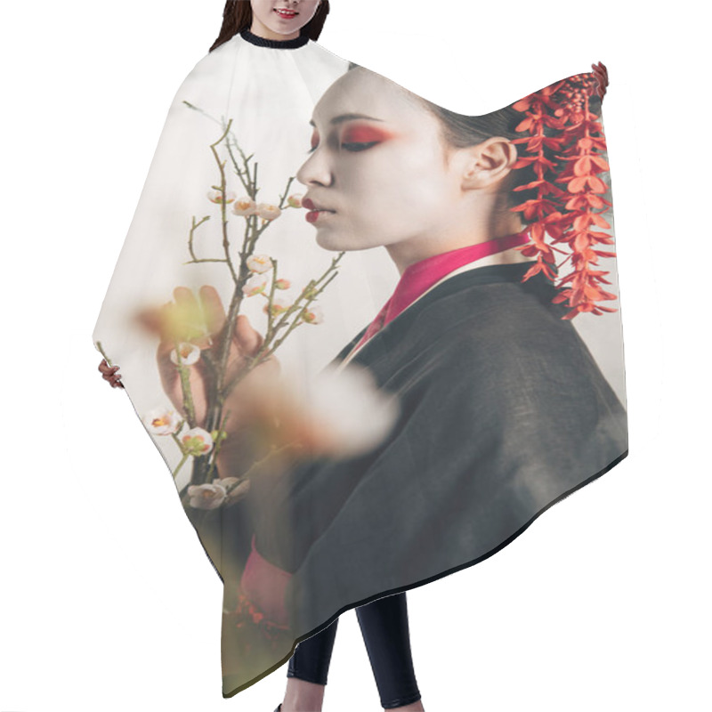 Personality  Selective Focus Of Beautiful Geisha In Black Kimono With Red Flowers In Hair And Sakura Branches In Smoke Hair Cutting Cape