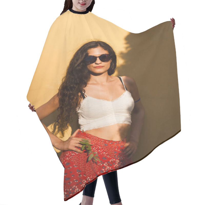 Personality  A Fashion-forward Young Woman Sporting Large Sunglasses And A Floral Skirt Stands Boldly Against A Warm Yellow Background. Hair Cutting Cape