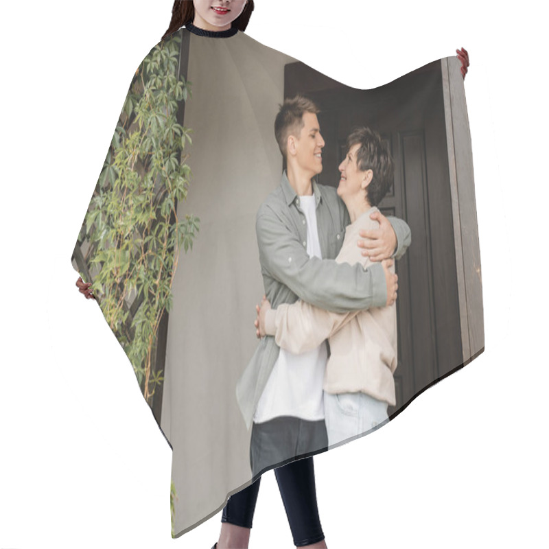 Personality  Side View Of Positive Young Man Hugging Middle Aged Mother While Celebrating Parents Day And Standing On Porch Of House In June, Quality Time With Parents Concept, Special Occasion Hair Cutting Cape