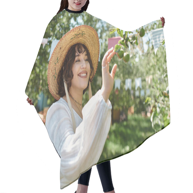 Personality  A Young Woman With Dark Hair, Wearing A Straw Hat And A White Blouse, Reaches Up To Pluck Fruit From A Tree In A Lush Summer Garden. Hair Cutting Cape