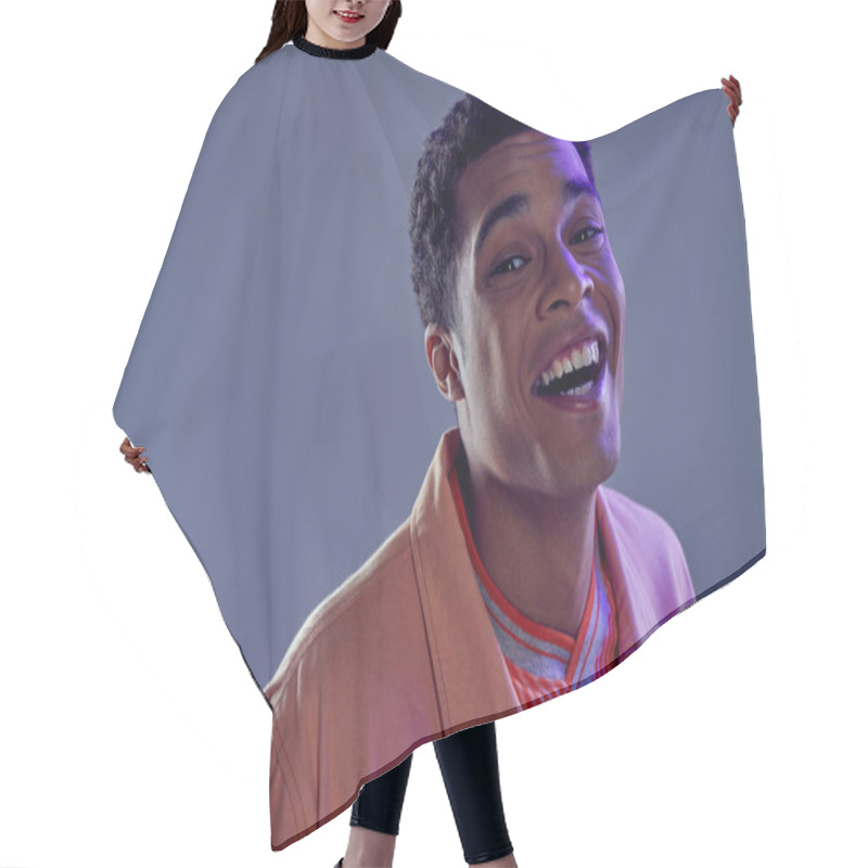 Personality  Portrait Of Joyous African American Guy In Peach Shirt Laughing On Grey Background With Blue Light Hair Cutting Cape