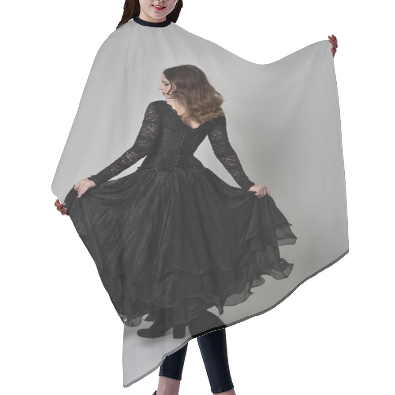 Personality  Full Length Portrait Of Brunette Girl Wearing Long Black Lace Gown Wit Corset. Standing Pose With Back To The Camera. Isolated On Grey Studio Background. Hair Cutting Cape