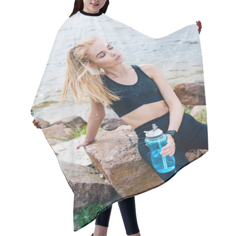 Personality  Blonde Sportswoman With Closed Eyes Holding Sport Bottle While Sitting On Stone Near Sea  Hair Cutting Cape