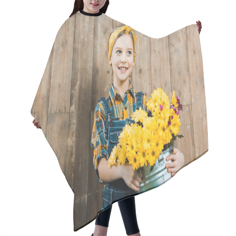 Personality  Cheerful Kid Holding Flowers In Bucket And Standing Near Wooden Fence Hair Cutting Cape