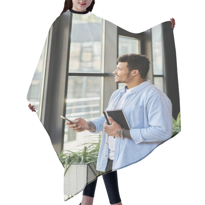 Personality  A Handsome Man Stands By The Window In Bright Sunlight, Holding A Notebook Thoughtfully. Hair Cutting Cape