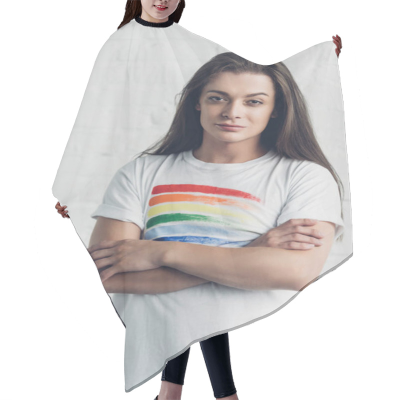 Personality  Young Transgender Woman In White T-shirt With Pride Flag Looking At Camera With Crossed Arms In Front Of White Brick Wall Hair Cutting Cape