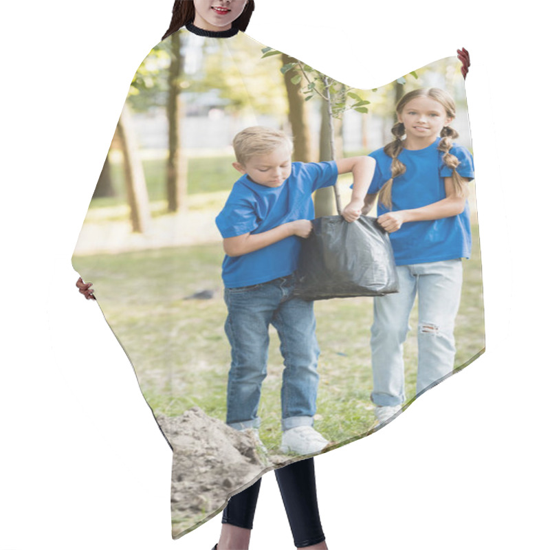 Personality  Brother And Sister Carrying Young Seedling In Park, Ecology Concept Hair Cutting Cape