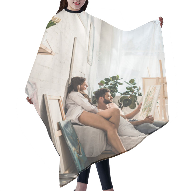 Personality  Side View Of Sexy Young Couple Looking At Painting While Man Lying In Bed And Girl Sitting Next To Guy Hair Cutting Cape