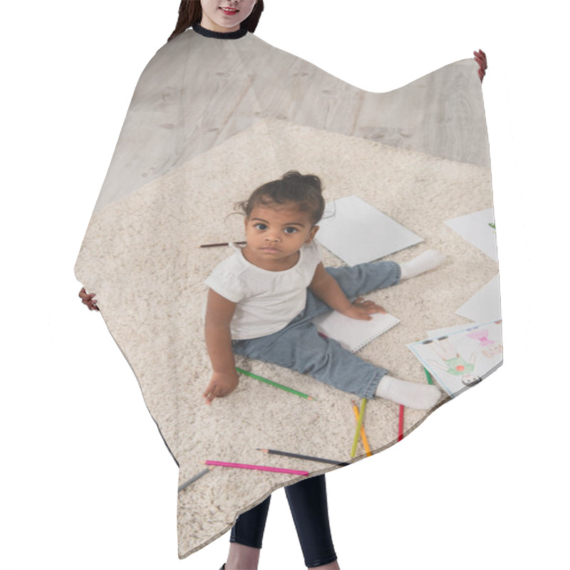 Personality  High Angle View Of African American Toddler Girl Sitting On Carpet Near Colorful Pencils And Drawings  Hair Cutting Cape