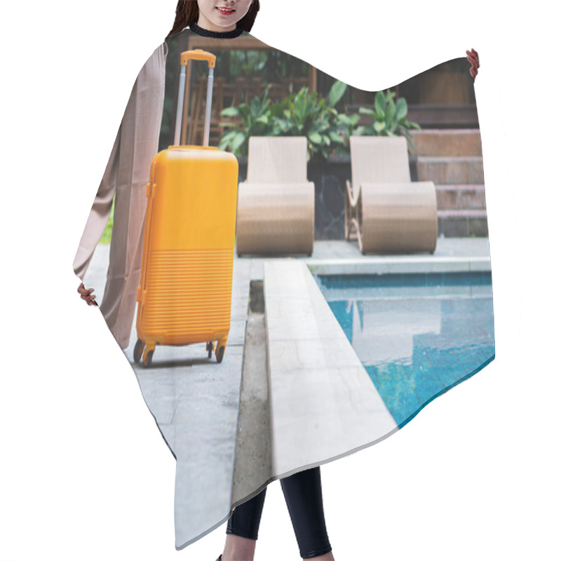 Personality  A Woman Walking By A Poolside With An Orange Suitcase, Wearing A Hat And Stylish Outfit. The Background Features Lush Greenery And A Wooden Structure, Creating A Tropical Vacation Vibe. Hair Cutting Cape