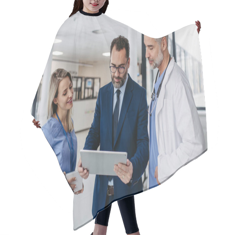 Personality  Pharmaceutical Sales Representative Presenting New Medication To Doctors In Medical Building, Showing On Tablet. Hospital Director Of Private Medical Clinic Talking With Doctors. Generous Donor Hair Cutting Cape