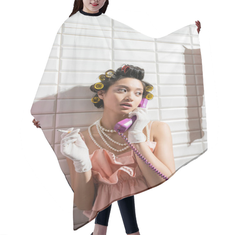 Personality  Fashionable And Asian Young Woman With Hair Curlers Standing In Pink Ruffled Top, Pearl Necklace And White Gloves Smoking And Talking On Retro Phone Near White Tiles, Housewife, Holding Cigarette  Hair Cutting Cape