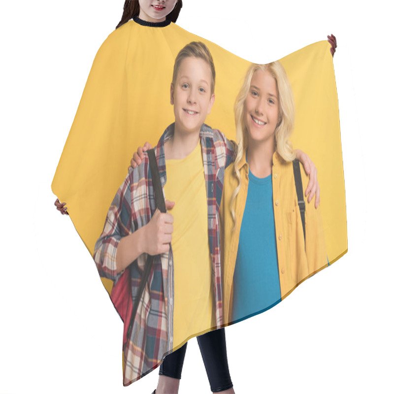 Personality  Smiling Schoolkids With Backpacks Hugging And Looking At Camera On Yellow Background  Hair Cutting Cape