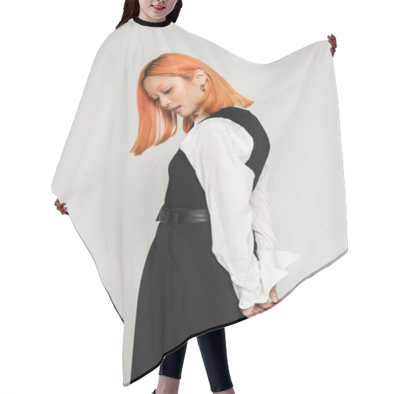 Personality  Side View Of Expressive And Young Asian Woman Posing With Hands Behind Back On Grey Background, Dyed Red Hair, White Shirt, Vest And Pants, Business Casual Fashion, Modern Lifestyle Hair Cutting Cape