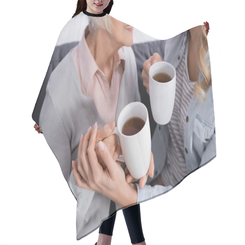 Personality  Cropped View Of Daughter Holding Cup And Touching Hand Of Senior Mother  Hair Cutting Cape