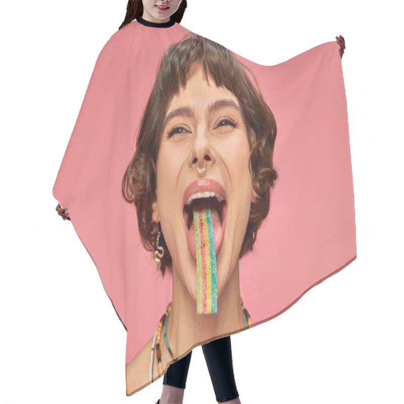 Personality  Cheerful Young Woman In Her 20s Tasting Sweet And Sour Candy Strip On Her Tongue, Pink Background Hair Cutting Cape