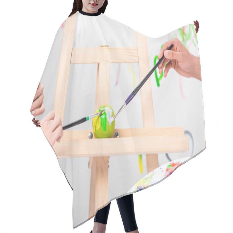 Personality  Close Up Of Adult Couple Painting Green Apple On Easel With Paintbrushes Hair Cutting Cape