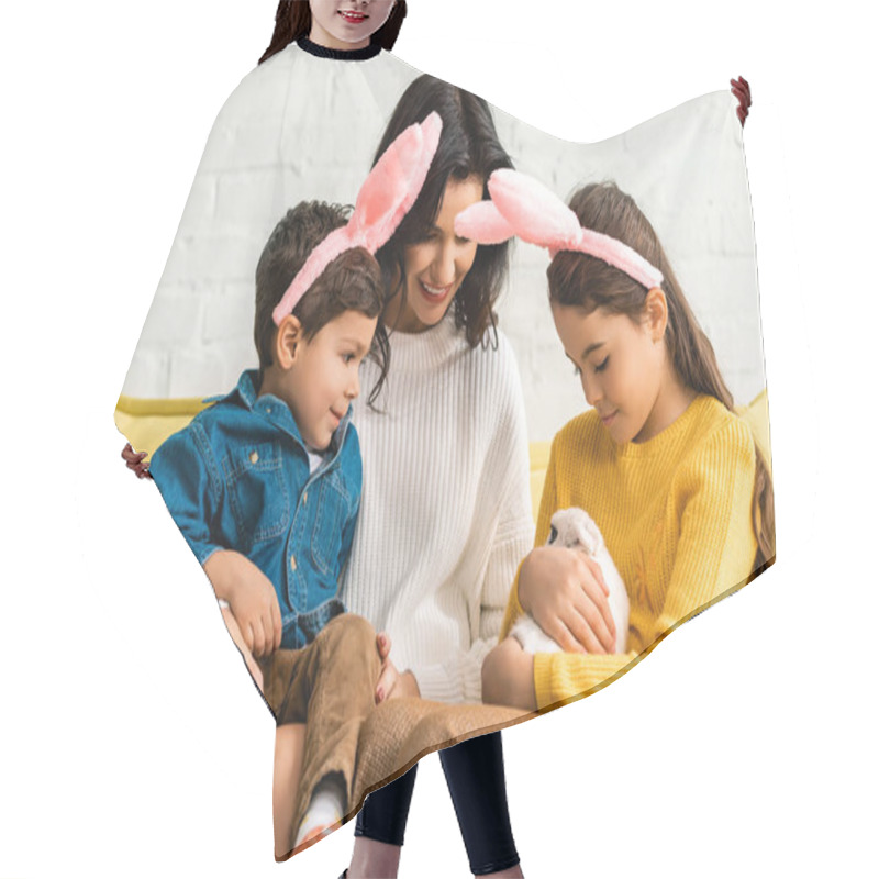 Personality  Happy Woman And Cheerful Children In Bunny Ears Sitting On Yellow Sofa With White Funny Rabbit Hair Cutting Cape