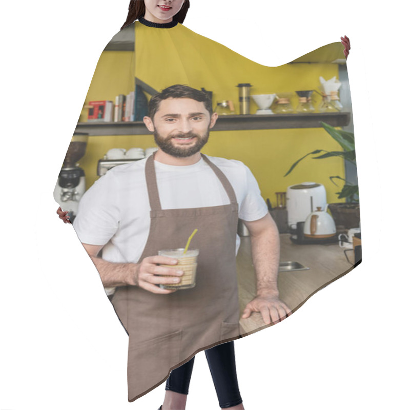 Personality  Positive Barista In Apron Holding Cold Coffee Drink In Glass And Smiling At Camera In Coffee Shop Hair Cutting Cape