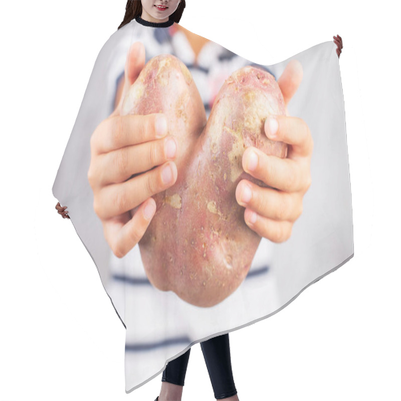 Personality  Boy Holds Ugly Potato In The Heart Shape On A Gray Background. Funny, Unnormal Vegetable Or Food Waste Concept Hair Cutting Cape