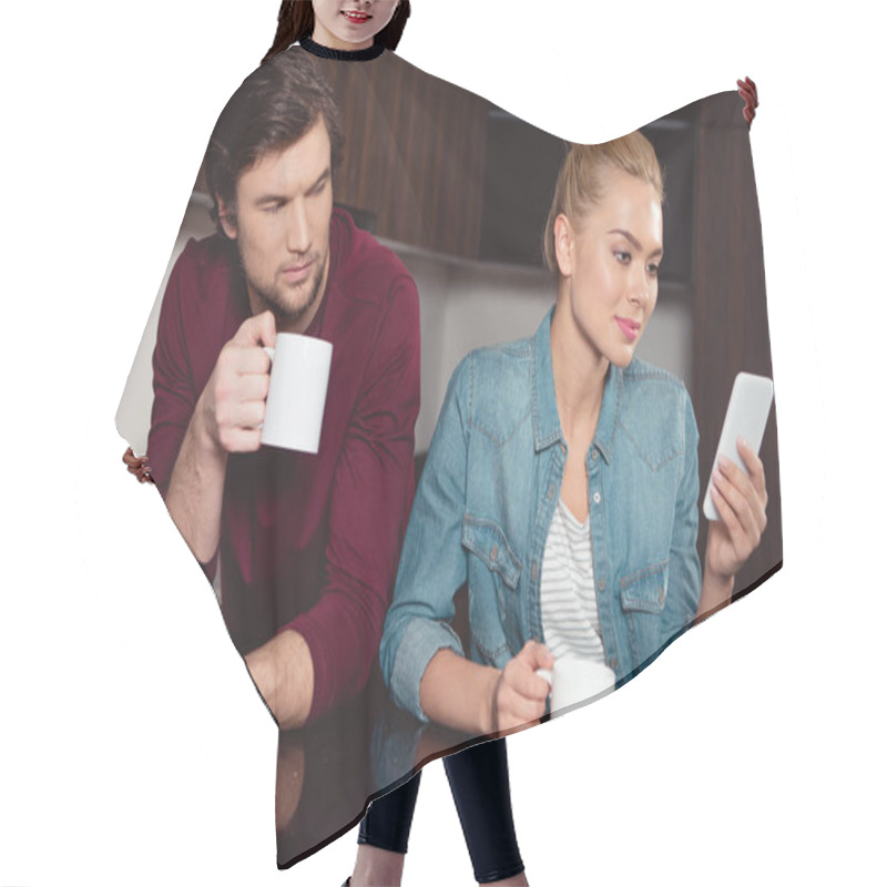 Personality  Jealous Husband Holding Coffee Cup And Looking At Wife Using Smartphone In Kitchen Hair Cutting Cape