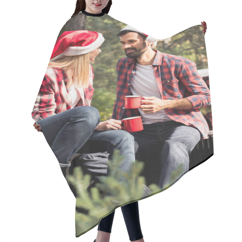 Personality  Happy Couple In Santa Hats Holding Red Cups While Sitting On Pickup Truck With Fir Tree For Christmas In Forest Hair Cutting Cape