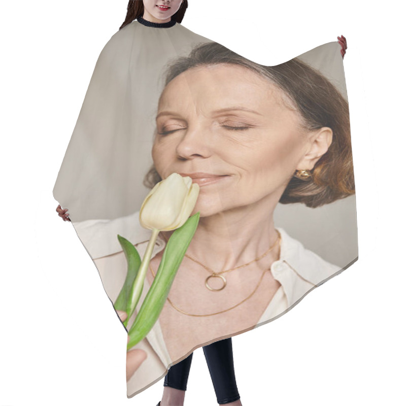 Personality  A Mature, Attractive Woman Comfortably Smelling A White Tulip. Hair Cutting Cape