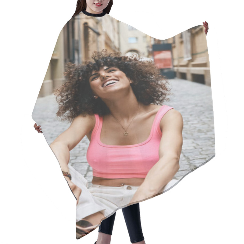 Personality  A Woman In Stylish Attire Sits On A Cobblestone Street In Europe, Smiling Brightly. Hair Cutting Cape