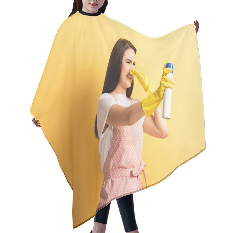 Personality  Displeased Housewife In Apron And Rubber Gloves Plugging Hose With Hand While Spraying Air Freshener On Yellow Background Hair Cutting Cape