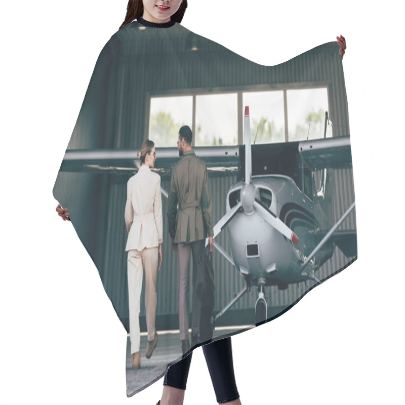 Personality  Rear View Of Man Carrying Bag And Walking With Stylish Girlfriend Near Hangar With Plane  Hair Cutting Cape